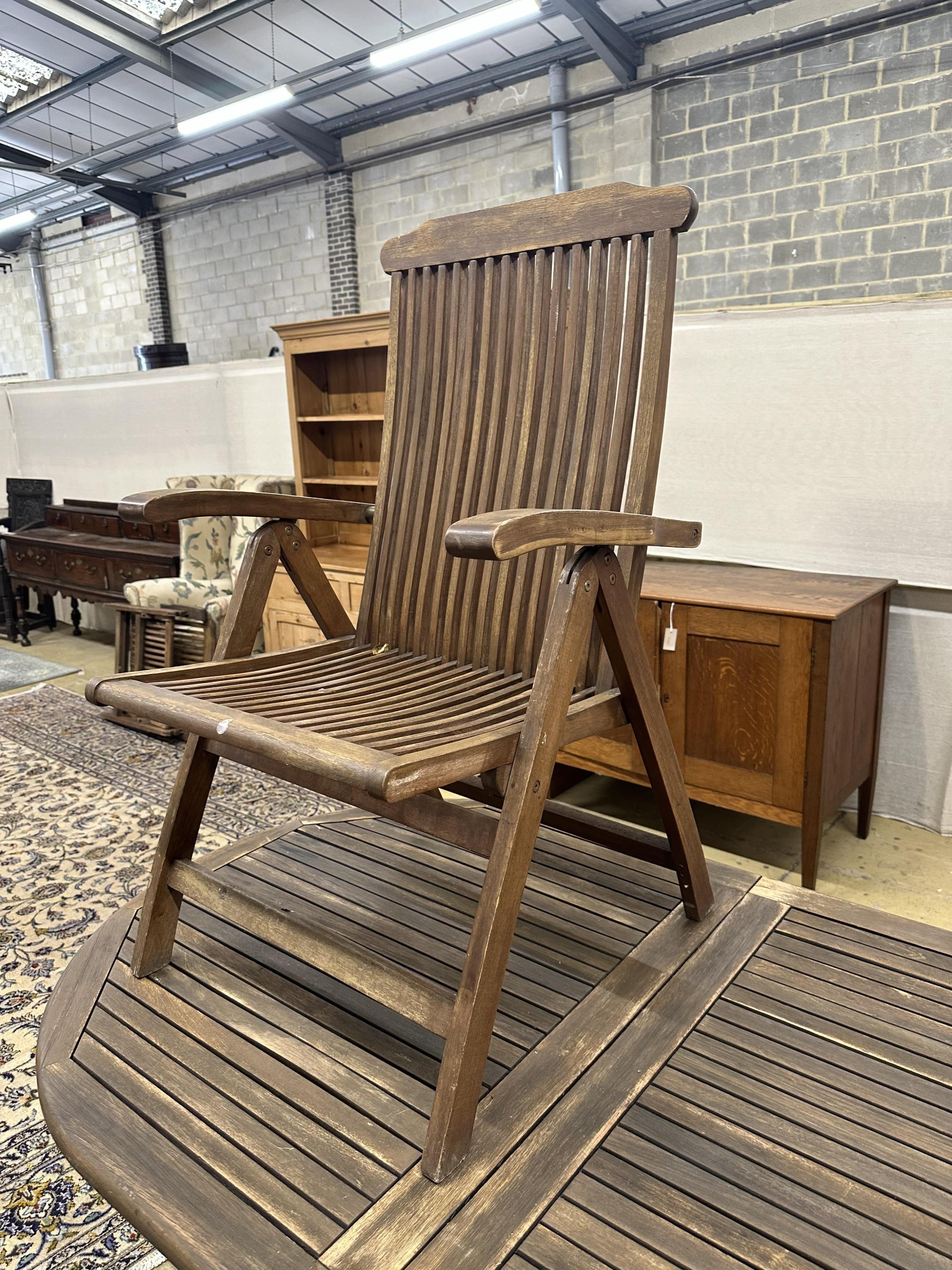 A weathered teak extending garden table, approximately 220cm extended, depth 100cm, height 74cm, together with six teak folding garden armchairs. Condition - fair